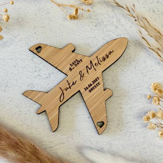 A personalised wooden airplane fridge magnet engraved with names and dates for wedding save the date invitation