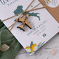 A wedding invitation card designed like a passport with a lemon design in yellow and green, tied with twine and a wooden airplane charm, with a kraft envelope