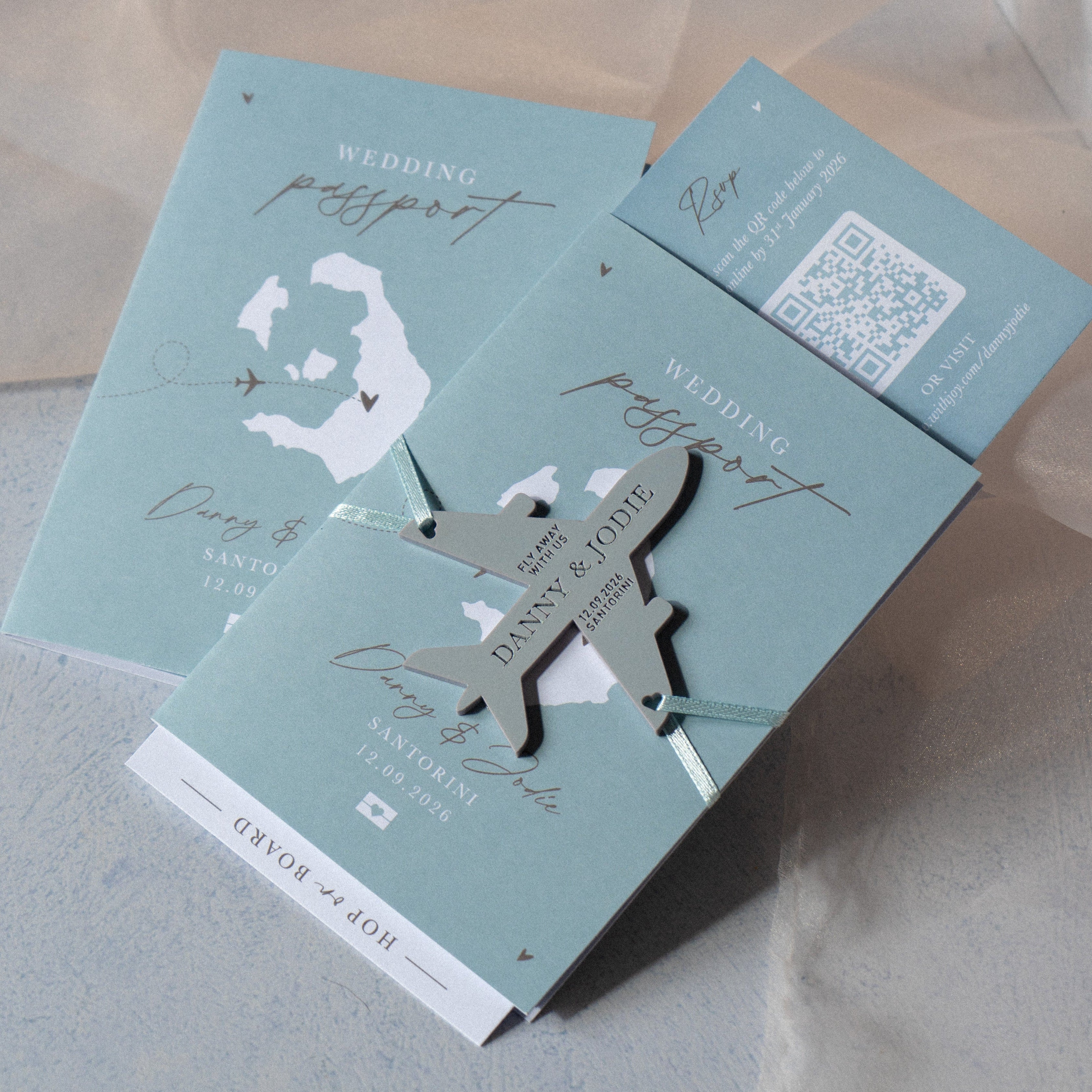dusty dusky blue passport style wedding invitation with plane fridge magnet keepsake and rsvp boarding pass card
