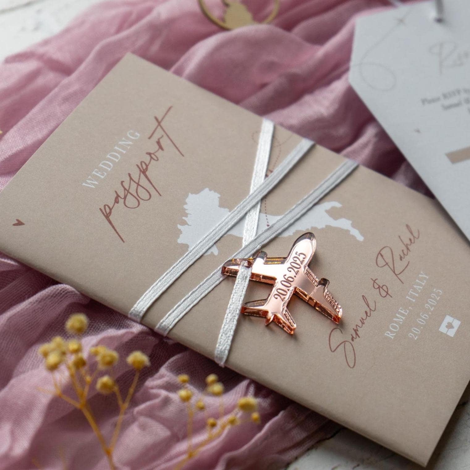 neutral beige wedding passport with a rose gold acrylic plane charm for a destination wedding abroad
